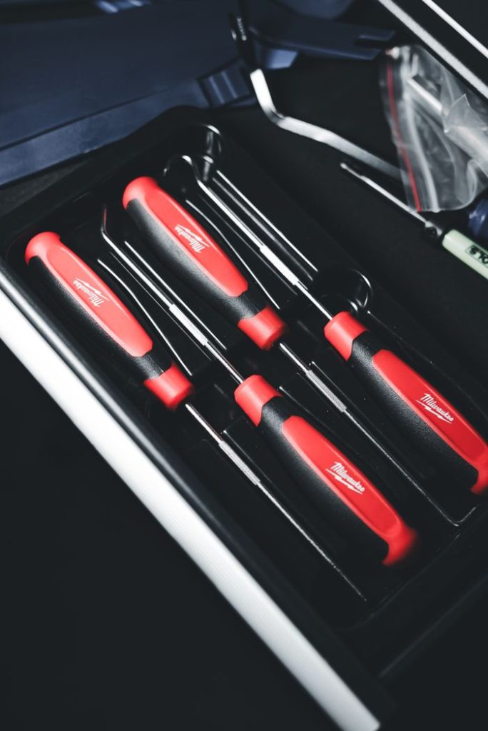 Vertical shot of a red and black screwdriver set neatly arranged in a toolbox, ready for use.