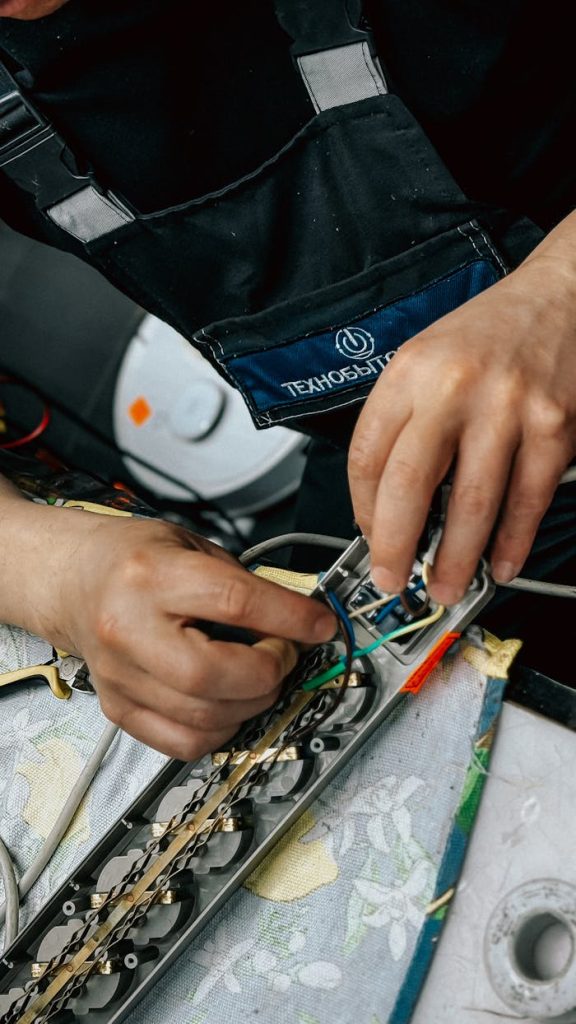 Close-up of a technicians hands working on electronic equipment wiring indoors.